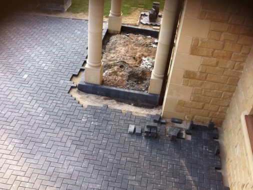 Charcoal block paved driveway meeting a curbrace around a portico to front of building