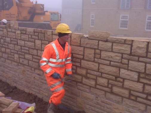 Random stone in a boundary wall, built for privacy, being jointed to match in with adjoining new-build properties